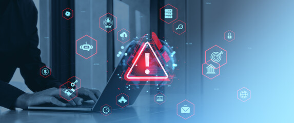 Cybersecurity alert warning symbol on laptop with business icons overlayed digitally.