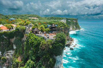 Bali's Most Iconic Landmark and popular tourist attraction Uluwatu Temple one of six key Bali temple perched on top mountain cliff on background amazing nature Bali, Indonesia Aerial view