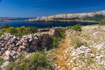Low walls made of stone built by locals on the trail leading from Baska to Vela Luka beach,