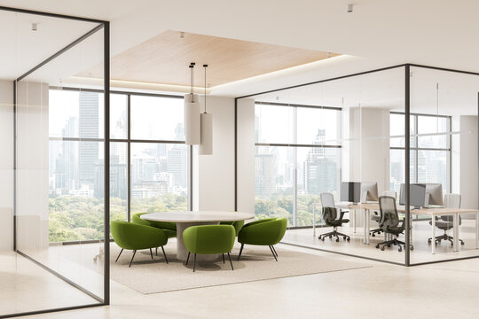 Modern office interior with round meeting table and green chairs in glass-walled space overlooking city skyline on a bright day. 3D Rendering