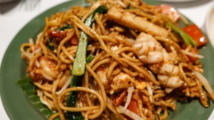close up of stir fried Malaysian noodles with choi sum, squid and prawns