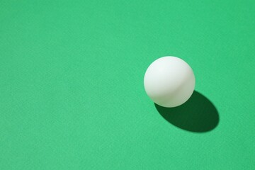 One ping pong ball on green background, closeup. Space for text