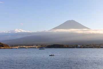 Sunset over Lake Kawaguchi with Mount Fuji in the background, floating clouds encircle the volcano slopes