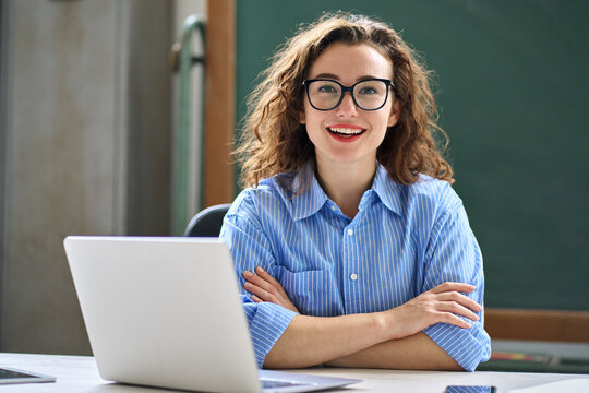 Smiling school professional online teacher coach advertising virtual distance students classes teaching remote education training. Young happy business woman sitting at work desk with laptop. Portrait
