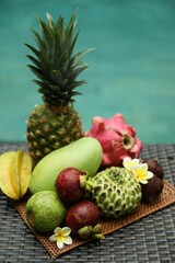 Different tropical fruit on wicker table near swimming pool