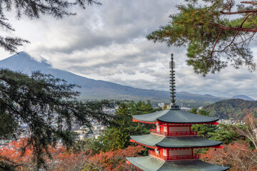 Chureito Pagoda framed by pine branches with Mount Fuji in the distance under dramatic clouds overlooking Fujiyoshida