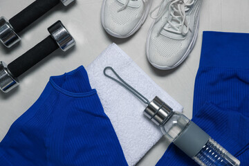 Sportswear, sneakers, dumbbells, towel and water bottle on gray textured background, flat lay