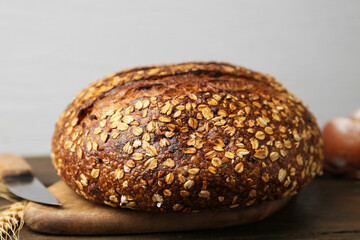 Freshly baked bread with oat flakes on wooden table against grey background, closeup