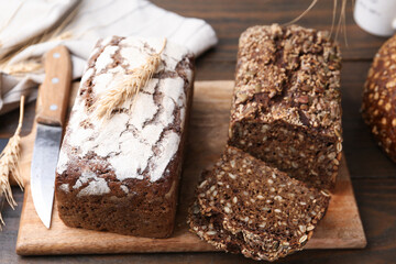 Freshly baked loaves of bread and spikes on wooden table, closeup