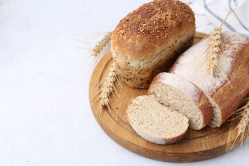 Freshly baked loaves of bread and spikes on light table, closeup. Space for text