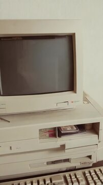 Vintage personal computer setup featuring beige monitor, keyboard, drives, old software, and mousepad on a wood desk with a retro vibe.