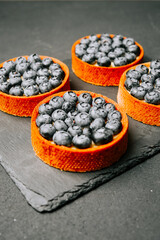Blueberry tarts with a vibrant orange crust served on a slate board