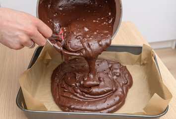 Raw brownie mass with pieces of bitter dark chocolate poured into a mold, homemade baking, real...