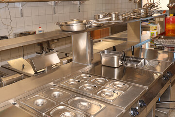 Immaculately clean commercial kitchen with stainless steel surfaces and cooking equipment, showcasing hygiene, organization, and professional food preparation environment.