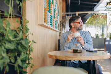 Senior man enjoying a cup of tea at a modern cafe