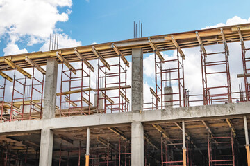 Obraz premium Construction progress of a modern building with scaffolding under a bright blue sky