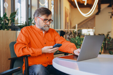 Senior Man Managing Finances with Laptop and Calculator in Modern Office