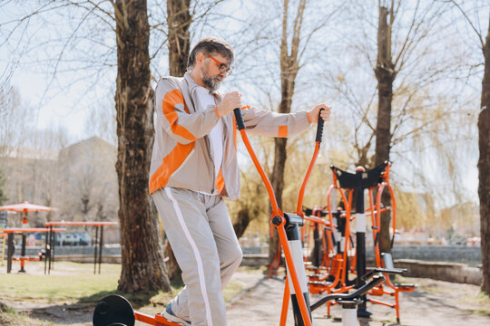 Senior man exercising on elliptical trainer in outdoor gym