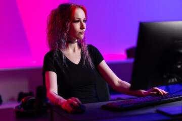 Focused female gamer interacting with computer in vibrant neon-lit gaming space