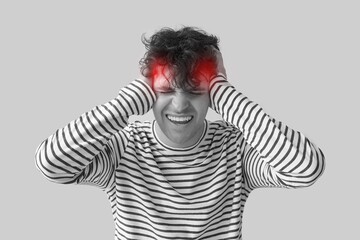 Young man suffering from headache on grey background