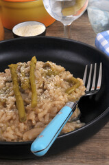 Risotto aux asperges vertes fait maison avec une fourchette servi dans une assiette en gros plan