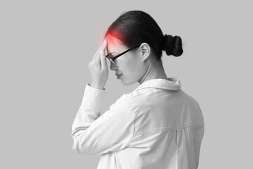 Young Asian woman suffering from headache on beige background. Brain Injury Awareness Month