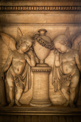 Couple of young angels, crying for the loss. Sculpture on ancient tombstone in an old Italian cemetery