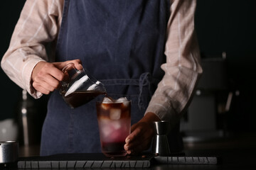 Female barista making cold brew coffee at table, closeup