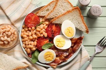 Plate of tasty English breakfast with boiled eggs on green wooden background