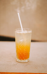Refreshing layered drink with straw served in a clear glass against a soft background