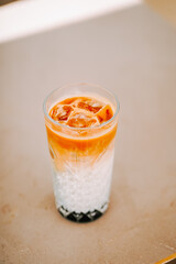 Delicious layered drink with ice in a clear glass on a neutral background