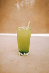 Refreshing green beverage served in a textured glass on a neutral background