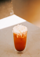 Delicious iced beverage topped with whipped cream served in a clear glass in a cafe setting