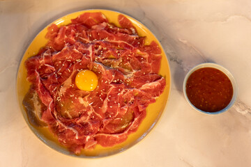 Marinated raw beef topped with egg yolk prepare for sukiyaki
