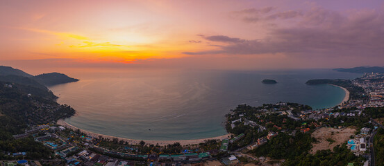  A stunning aerial view of the Andaman Sea at sunset, overlooking a coastal town in Phuket,...