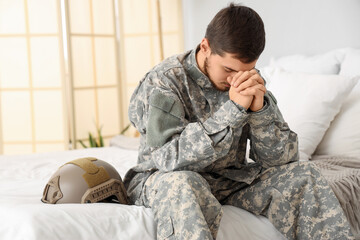 Young male soldier praying in bedroom