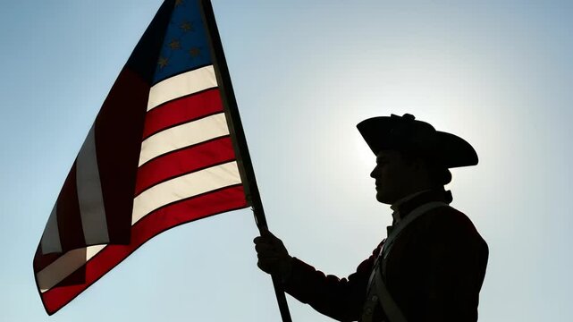 Revolutionary war soldier silhouetted with waving American flag on bright sky