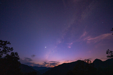 Milky Way above mountains at night in autumn. Landscape with mountain valley, low clouds, purple starry sky with milky way. The Milky Way shines on a cold night in the north of Thailand