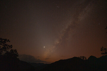 Milky Way above mountains at night in autumn. Landscape with mountain valley, low clouds, purple starry sky with milky way. The Milky Way shines on a cold night in the north of Thailand