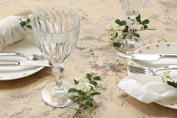 Beautiful table setting with plates, cutlery, glasses, napkins and blooming branches on grunge background, closeup