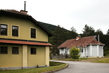 Rural houses with tiled roofs surrounded by hills and pine trees in Mokra Gora. Serbia country.