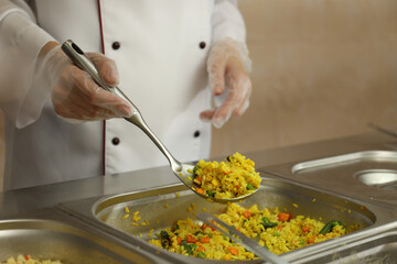 School canteen worker at serving line, closeup. Tasty food