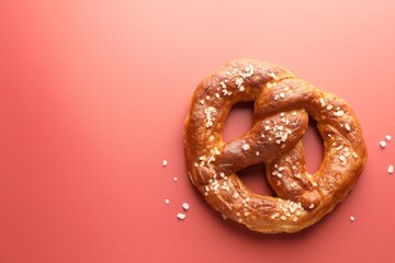 Tasty pretzel with salt on red background, top view. Space for text