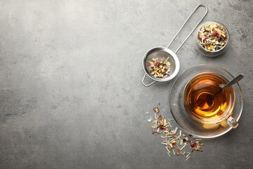 Aromatic herbal tea and dry leaves on grey table, flat lay. Space for text