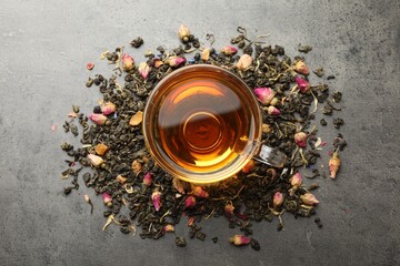 Aromatic herbal tea, dry leaves and flowers on grey table, flat lay