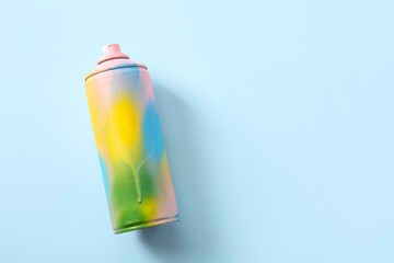Colorful spray paint can on blue background