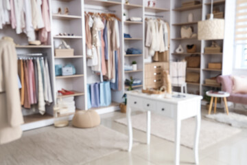 Blurred view of stylish boutique with shelves, clothes and table