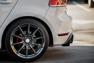 Rear view of a white car highlighting the back wheel and brake system. The car features a shiny,...