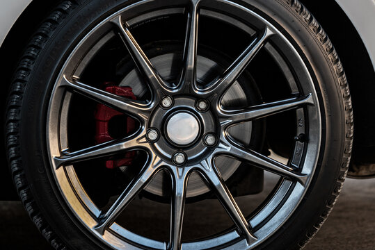 A close-up of an alloy car wheel featuring a multi-spoke design. The metallic spokes have a dark, polished finish, contrasting with the silver center cap. 