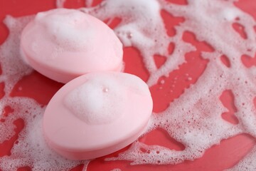 Soap bars with foam on red background, closeup. Space for text